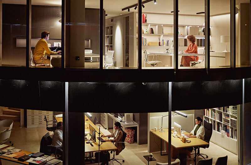 Two-story view of a modern office with workers at dusk.